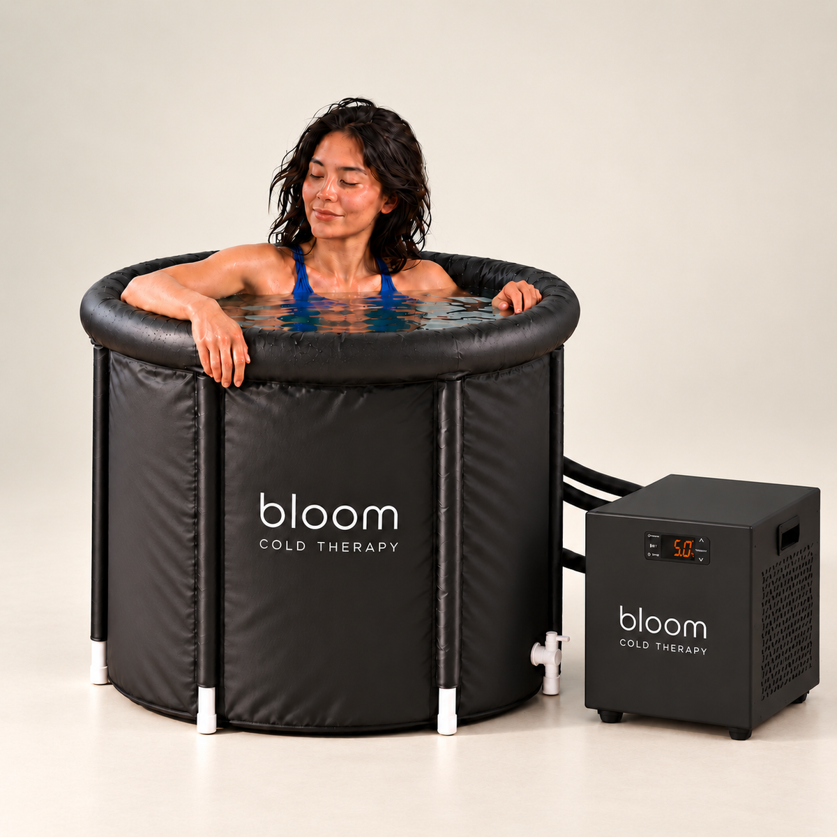 Woman relaxing in the Bloom Ice Core tub with compact chiller beside it on a soft ivory studio backdrop.
